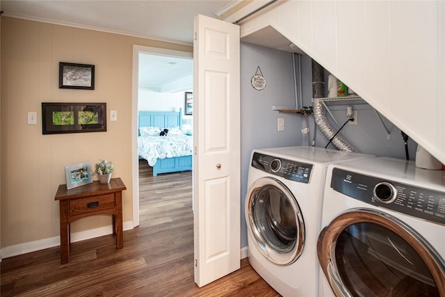 clothes washing area with laundry area, baseboards, ornamental molding, wood finished floors, and washer and dryer