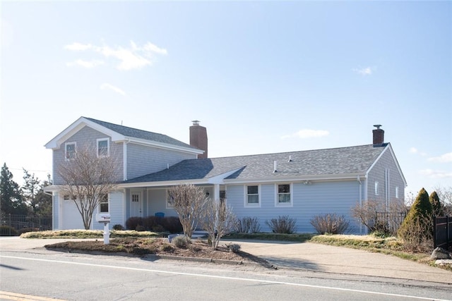 view of front of house with a shingled roof, concrete driveway, a chimney, an attached garage, and fence