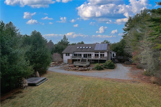 back of house featuring solar panels, a lawn, and a wooden deck