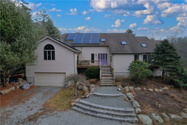 view of front of house with solar panels, a garage, and a wooden deck