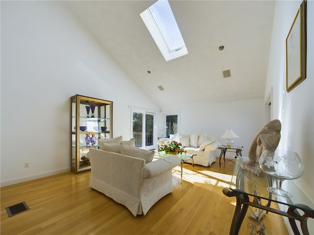 living room with light wood-type flooring, a skylight, and high vaulted ceiling