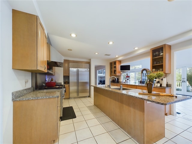 kitchen featuring stainless steel built in refrigerator, a kitchen bar, light tile patterned flooring, and sink