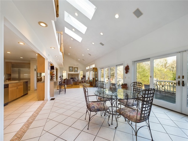 tiled dining space featuring french doors, sink, high vaulted ceiling, and a skylight