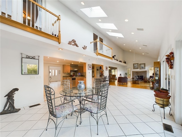 dining room featuring a skylight, high vaulted ceiling, and light tile patterned floors