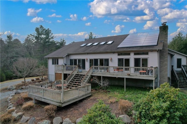 rear view of house featuring a wooden deck and solar panels