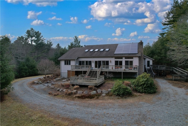 view of front facade featuring solar panels and a wooden deck