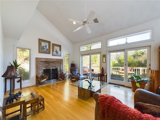 living room featuring french doors, ceiling fan, light hardwood / wood-style flooring, high vaulted ceiling, and a fireplace