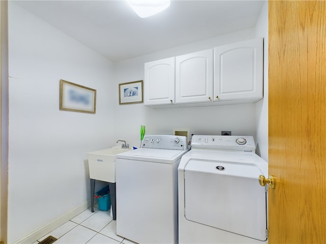 washroom featuring separate washer and dryer, light tile patterned floors, and cabinets