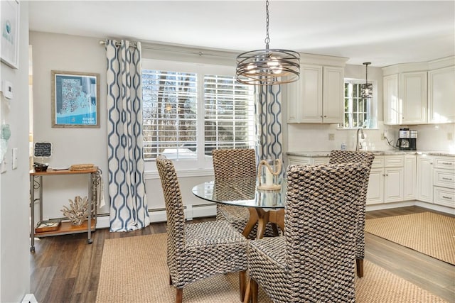 dining area with sink, a notable chandelier, and hardwood / wood-style flooring