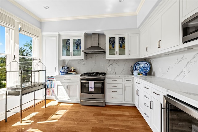 kitchen with backsplash, gas range, wall chimney exhaust hood, built in microwave, and beverage cooler