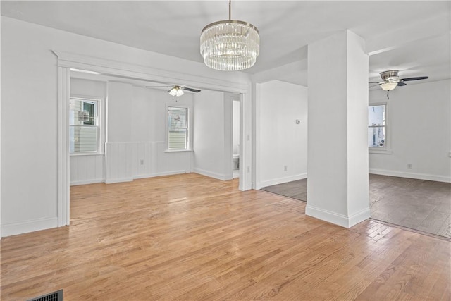 unfurnished living room featuring light hardwood / wood-style floors and ceiling fan with notable chandelier