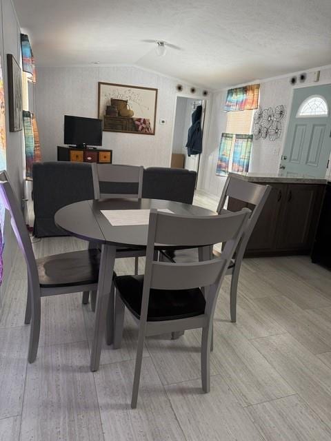 dining space featuring light wood-type flooring and lofted ceiling