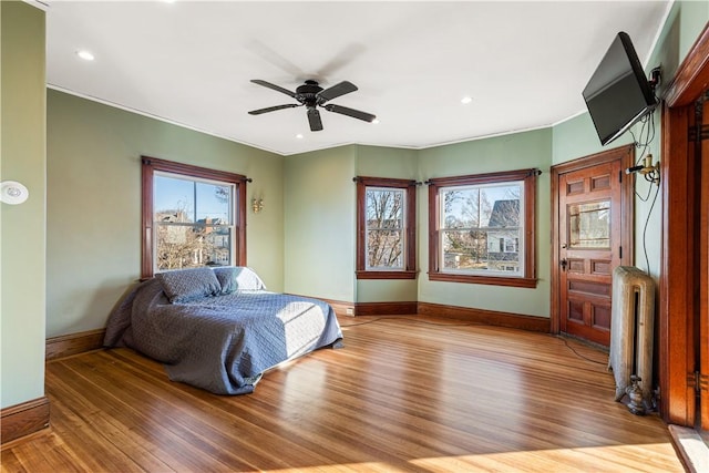 bedroom with ceiling fan, radiator heating unit, and light wood-type flooring