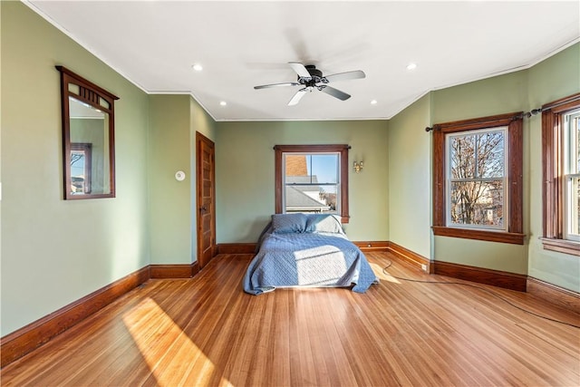 bedroom featuring hardwood / wood-style flooring, ceiling fan, and multiple windows