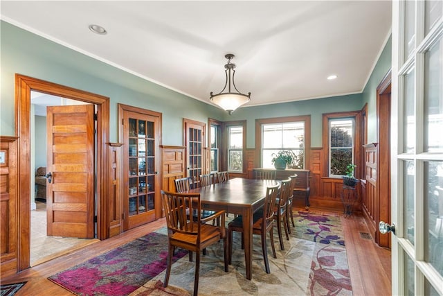 dining room with crown molding, french doors, and light hardwood / wood-style floors