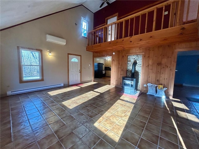 unfurnished living room featuring a wood stove, ceiling fan, a baseboard radiator, a wall mounted AC, and wood walls