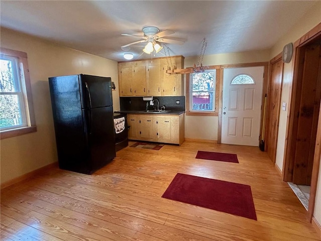 kitchen featuring black refrigerator, sink, ceiling fan, tasteful backsplash, and light hardwood / wood-style floors