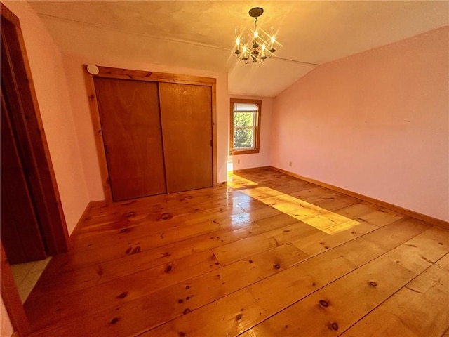 unfurnished bedroom with a closet, light hardwood / wood-style flooring, a chandelier, and lofted ceiling