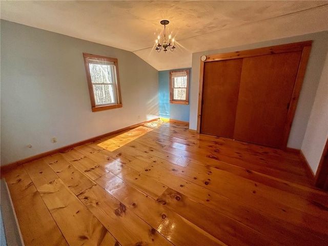 unfurnished bedroom with light hardwood / wood-style floors, an inviting chandelier, a closet, and lofted ceiling