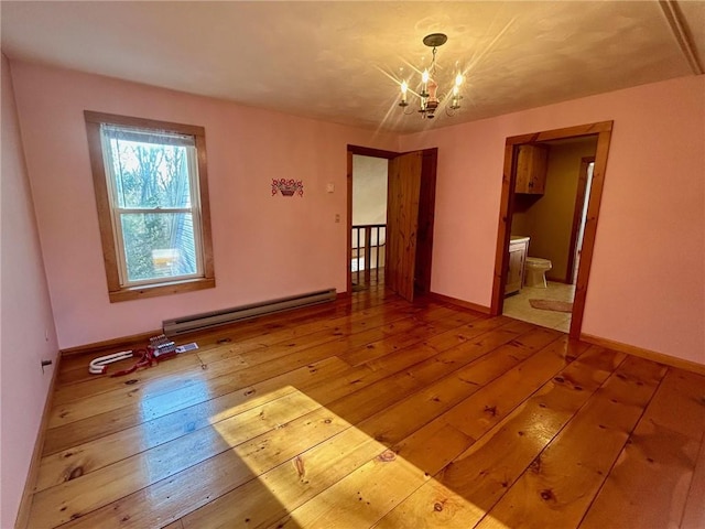 empty room featuring hardwood / wood-style floors, a baseboard radiator, and a notable chandelier