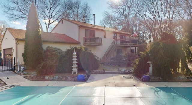 rear view of house featuring a balcony and a covered pool