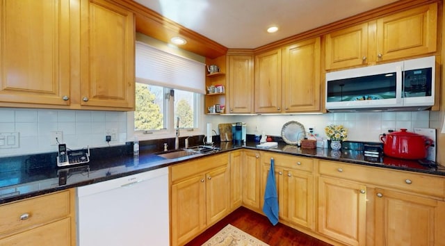 kitchen with sink, white dishwasher, backsplash, dark stone counters, and dark hardwood / wood-style floors