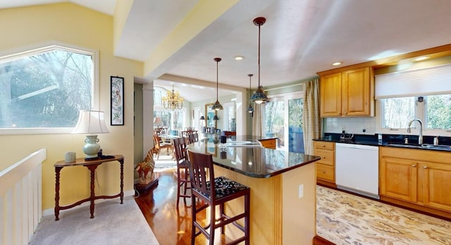 kitchen featuring sink, a breakfast bar, dishwasher, and lofted ceiling