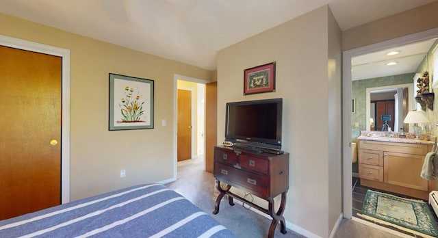 bedroom featuring baseboard heating, ceiling fan, and connected bathroom