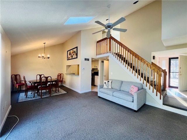 living room featuring dark colored carpet, ceiling fan with notable chandelier, a skylight, and high vaulted ceiling