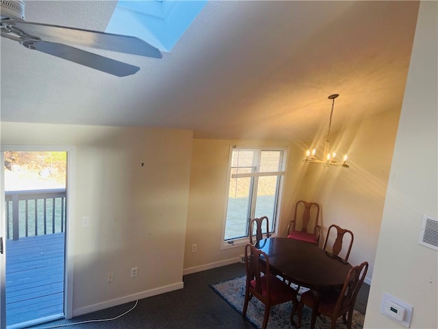 carpeted dining space with ceiling fan with notable chandelier and a skylight