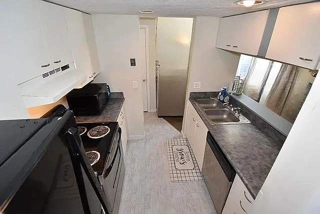 kitchen with electric range, sink, light hardwood / wood-style floors, a textured ceiling, and white cabinets