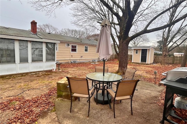 view of patio with an outdoor structure, fence, a sunroom, a shed, and outdoor dining space