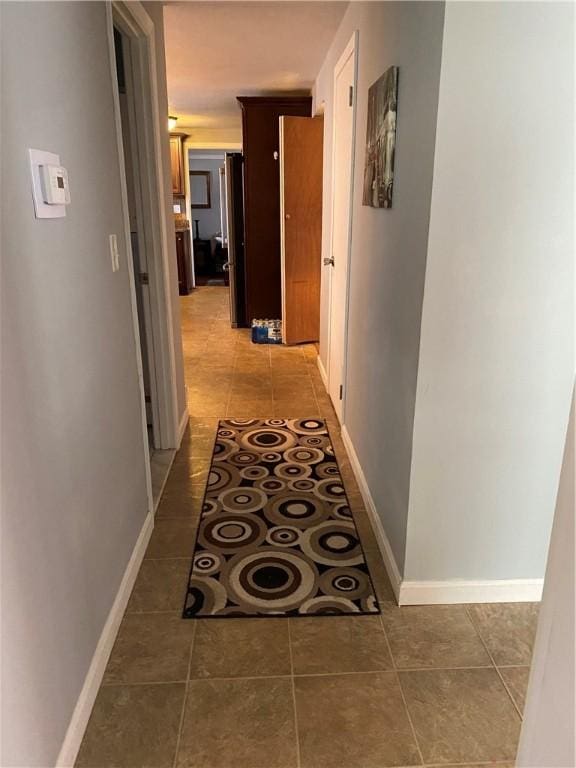 hall featuring light tile patterned flooring and baseboards