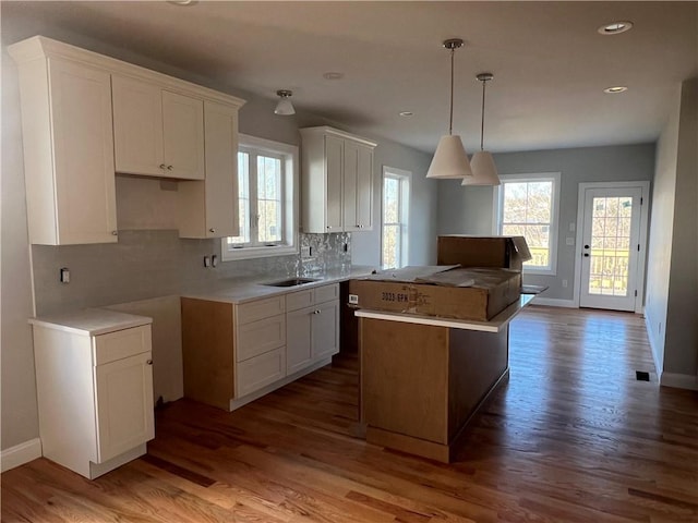 kitchen with decorative backsplash, a kitchen island, pendant lighting, hardwood / wood-style flooring, and white cabinetry