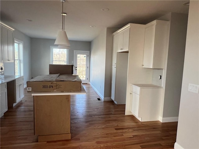 kitchen with pendant lighting, white cabinets, a wealth of natural light, a kitchen island, and dark hardwood / wood-style flooring