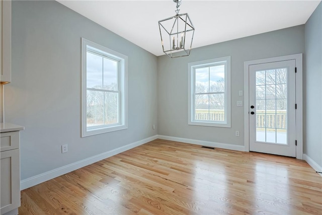 unfurnished dining area featuring a chandelier and light hardwood / wood-style flooring