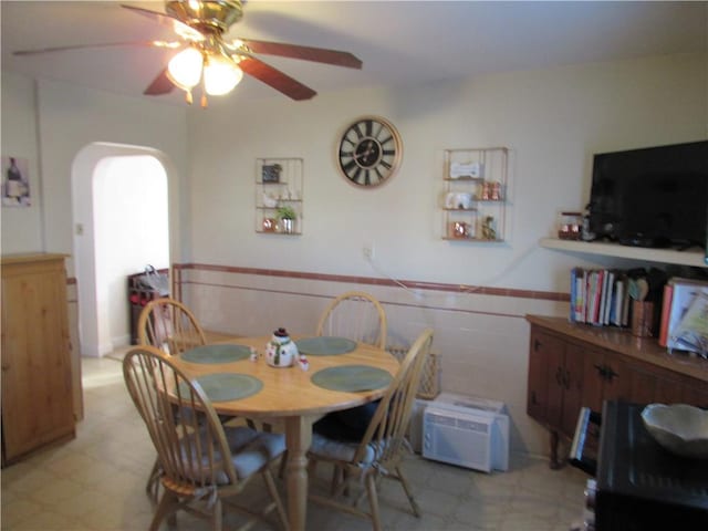 dining space featuring an AC wall unit, tile walls, and ceiling fan