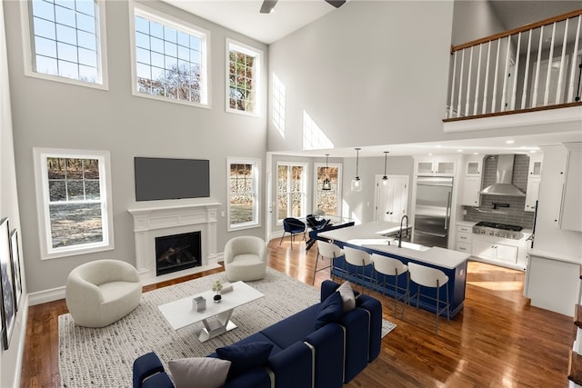 living room with dark hardwood / wood-style flooring, a towering ceiling, plenty of natural light, and ceiling fan