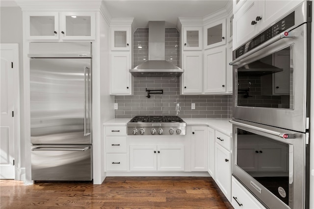 kitchen with stainless steel appliances, white cabinetry, dark hardwood / wood-style floors, and wall chimney exhaust hood