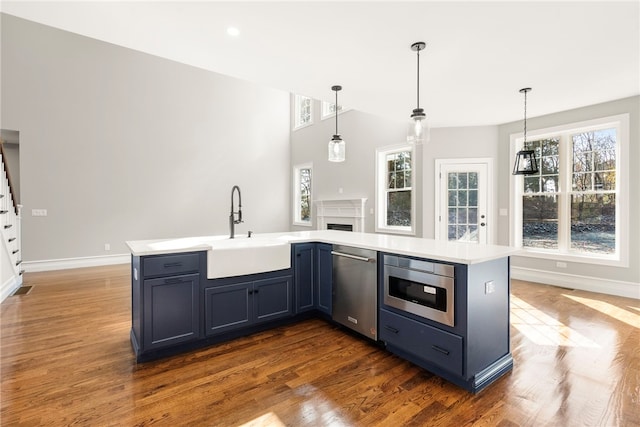 kitchen featuring built in microwave, sink, a healthy amount of sunlight, stainless steel dishwasher, and decorative light fixtures