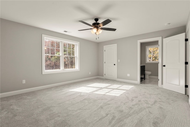 unfurnished bedroom with light colored carpet, ensuite bath, and ceiling fan