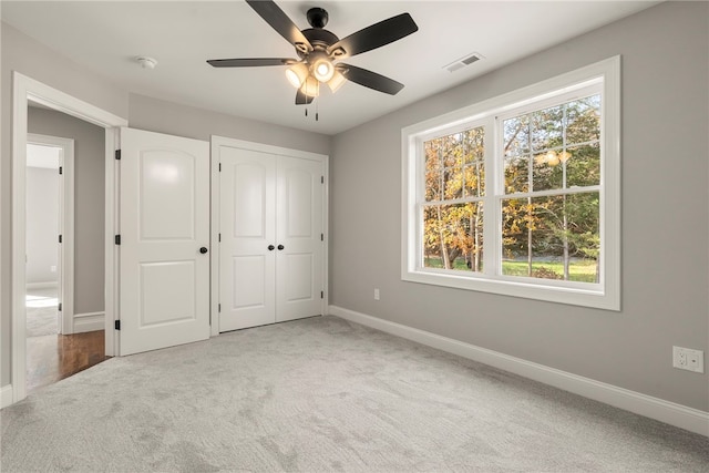 unfurnished bedroom with carpet, a closet, and ceiling fan