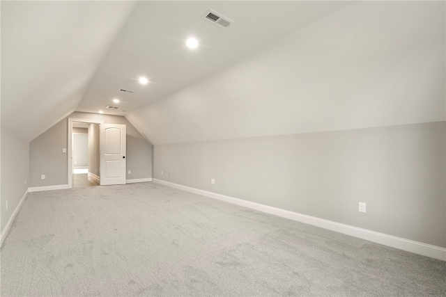 additional living space featuring light carpet and vaulted ceiling