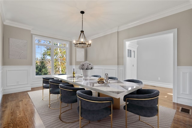 dining area featuring wood-type flooring, crown molding, and a chandelier