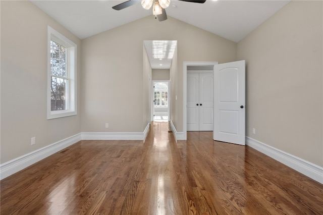 unfurnished bedroom featuring ceiling fan, a closet, wood-type flooring, and lofted ceiling