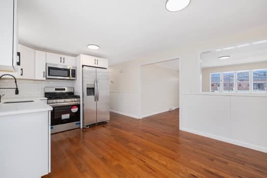 kitchen featuring sink, tasteful backsplash, dark hardwood / wood-style floors, white cabinets, and appliances with stainless steel finishes