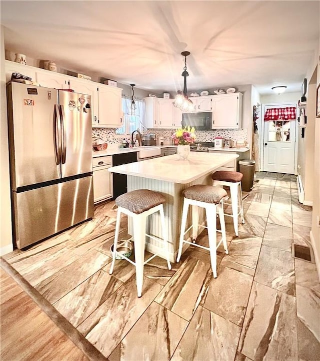 kitchen featuring stainless steel appliances, white cabinets, and a center island