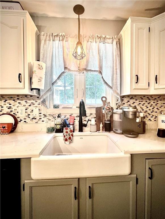 kitchen featuring sink, pendant lighting, white cabinets, and backsplash