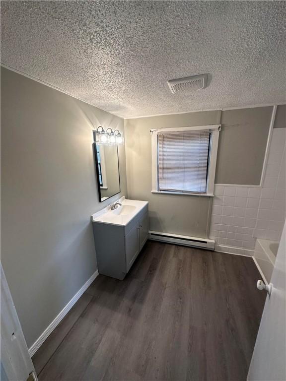 bathroom featuring a bathtub, vanity, a textured ceiling, baseboard heating, and hardwood / wood-style floors