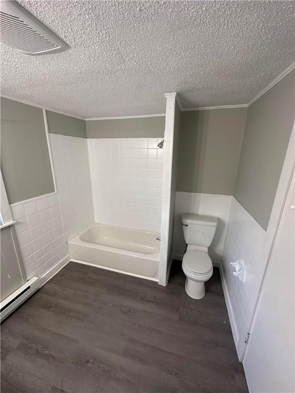 bathroom with tub / shower combination, wood-type flooring, a textured ceiling, and toilet